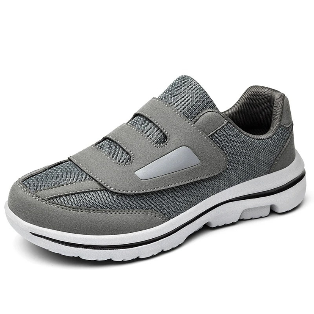 Chaussure de sport grise avec fermeture velcro, semelle blanche antidérapante. Confortable et légère, idéale pour marche et activités quotidiennes.