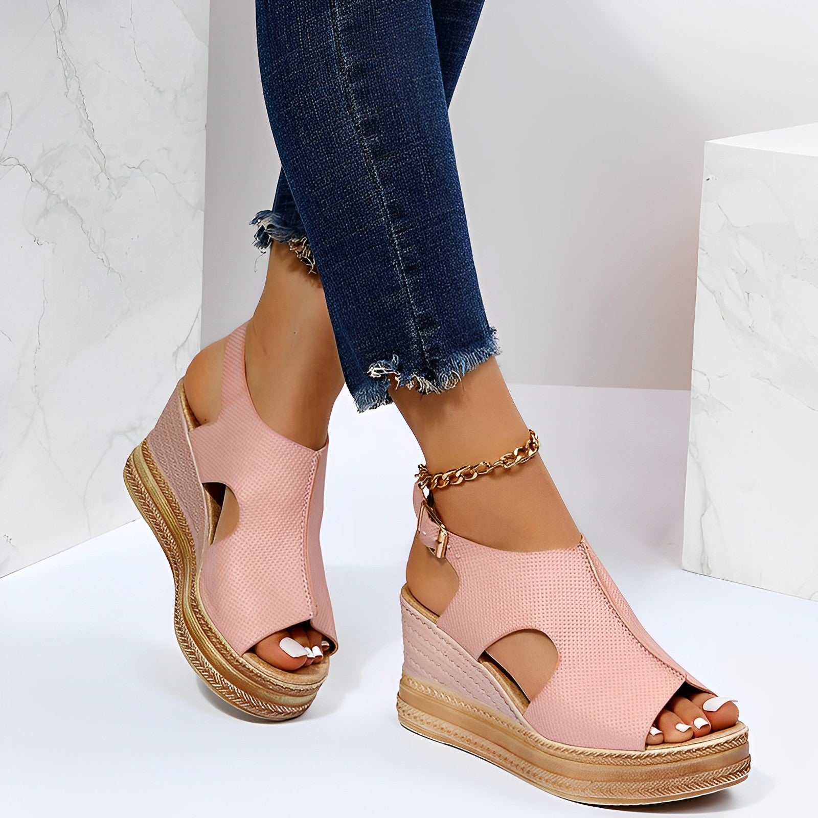 Sandales compensées roses pour femme, en cuir texturé, avec talon en liège, portées avec un jean bleu. Chaussures d'été élégantes et tendance.