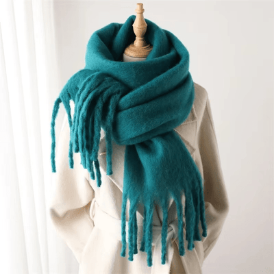 Écharpe en laine turquoise sur mannequin, texture douce et épaisse, franges longues, idéale pour l'hiver, accessoire mode chaud et élégant.