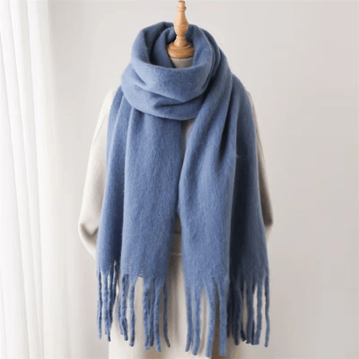 Écharpe en laine bleue avec franges, posée sur un mannequin, fond blanc. Accessoire mode hiver, chaud et élégant, tendance et confortable.