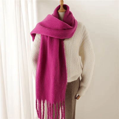 Écharpe rose fuchsia en laine sur mannequin, associée à un pull blanc texturé. Accessoire mode hiver, tendance et élégant.