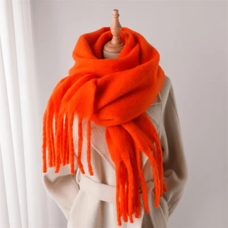 Écharpe orange vif en laine, drapée sur un mannequin beige, avec franges longues. Accessoire mode hiver, tendance et chaud.