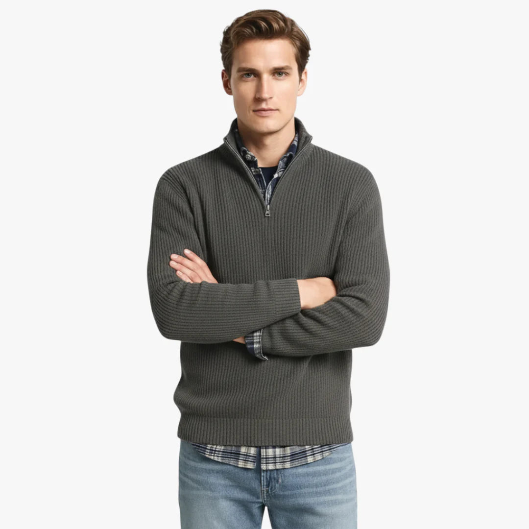Homme portant un pull gris à col zippé, chemise à carreaux bleue et jeans. Mode masculine décontractée, style automne-hiver.