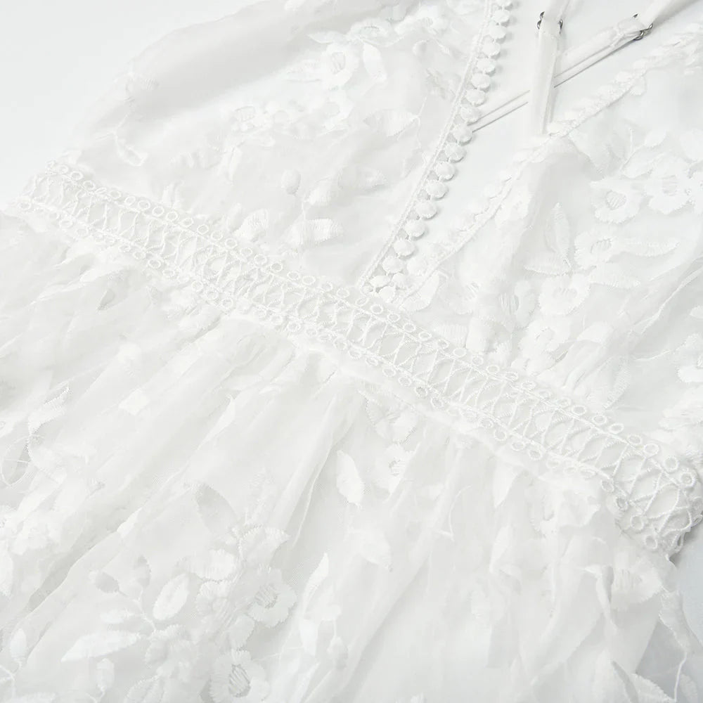 Robe en dentelle blanche avec motifs floraux, manches longues et boutons délicats, idéale pour mariage ou cérémonie élégante.