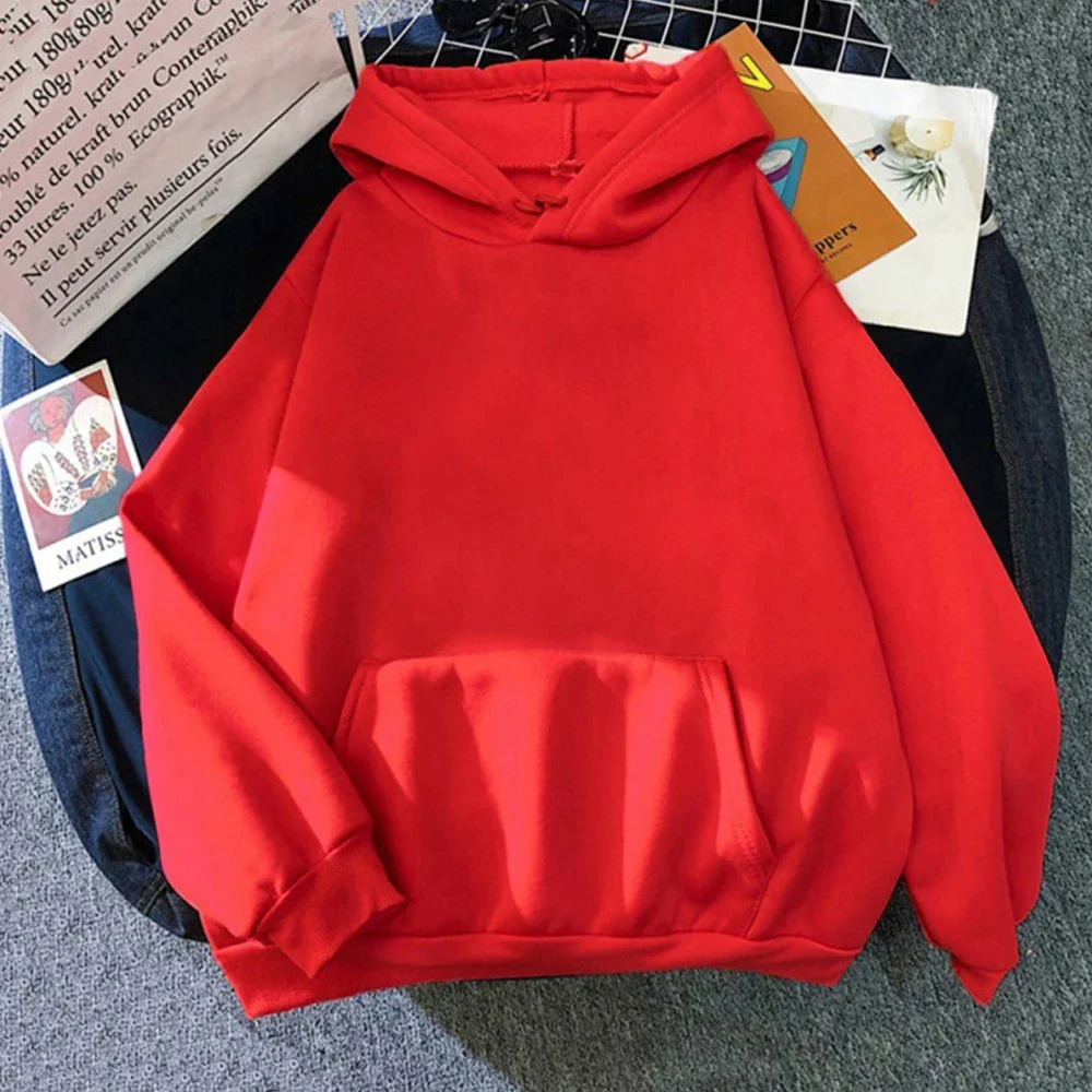 Sweat à capuche rouge vif, manches longues, poche kangourou, posé sur un fond gris. Mode décontractée, tendance automne-hiver, vêtement unisexe.