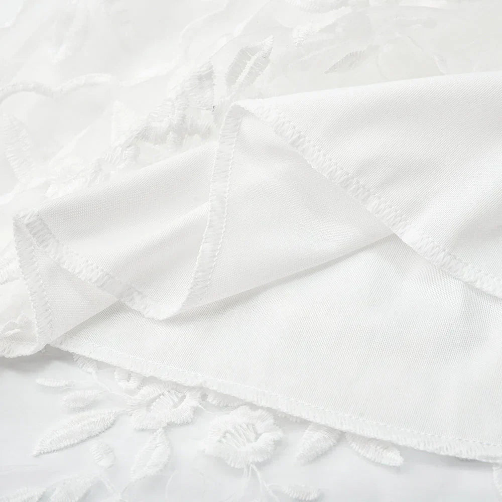 Tissu en dentelle blanche avec motifs floraux, texture délicate et élégante, idéal pour robes de mariée et décoration intérieure raffinée.