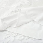 Tissu en dentelle blanche avec motifs floraux, texture délicate et élégante, idéal pour robes de mariée et décoration intérieure raffinée.