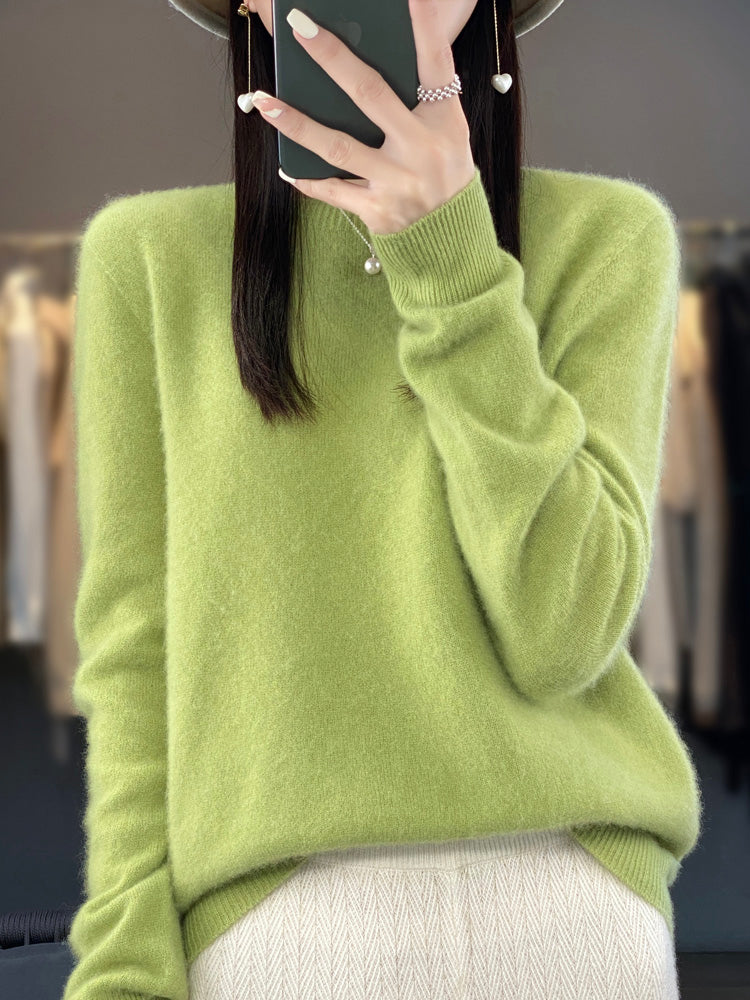 Femme portant un pull vert en cachemire, tenant un smartphone, mode automne-hiver, style élégant et décontracté, vêtements tendance.