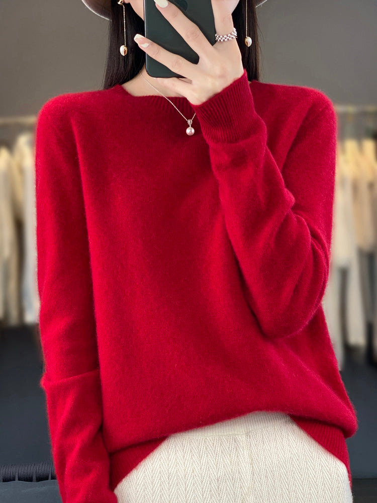 Femme portant un pull rouge en laine, tenant un smartphone. Mode automne-hiver, style élégant et décontracté, accessoires minimalistes.