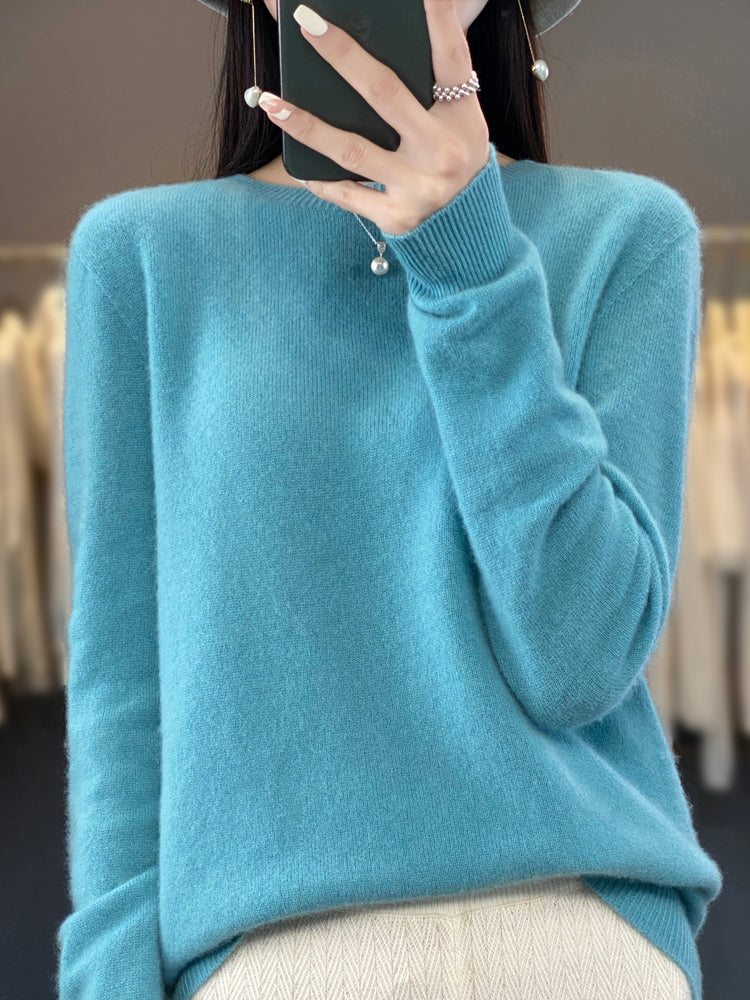 Femme portant un pull en cachemire bleu, tenant un smartphone. Mode automne-hiver, vêtement chaud et élégant, style décontracté.