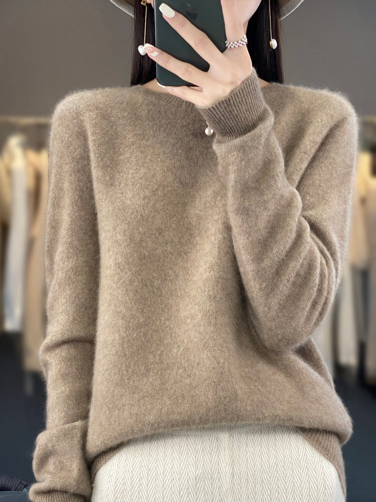 Femme portant un pull en cachemire beige, tenant un smartphone. Mode automne-hiver, style élégant et confortable. Arrière-plan flou de vêtements.