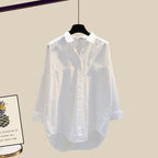 Chemise blanche en coton suspendue sur cintre, manches longues, col classique, style décontracté. Fond beige, affiche avec ananas visible à gauche.