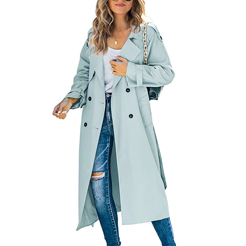 Femme portant un trench-coat bleu clair, jeans déchirés et t-shirt blanc, accessoirisé d'un sac à chaîne dorée. Mode automne chic et décontractée.