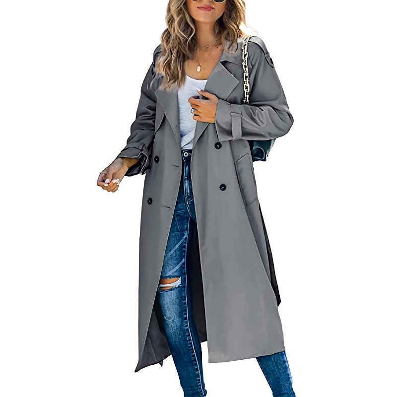 Femme portant un trench-coat gris élégant, jeans déchirés et sac à main chaîne, mode automne chic, style urbain moderne.