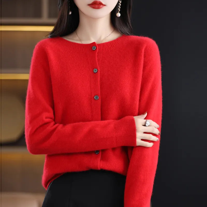 Femme portant un cardigan rouge en cachemire, boutons noirs, manches longues, posant élégamment. Mode automne-hiver, style chic et tendance.