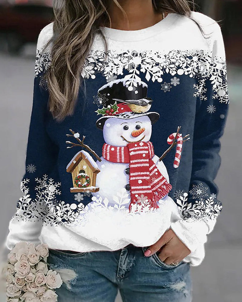 Femme portant un pull de Noël avec motif bonhomme de neige, écharpe rouge, chapeau noir, flocons de neige, tenant un bouquet de fleurs.