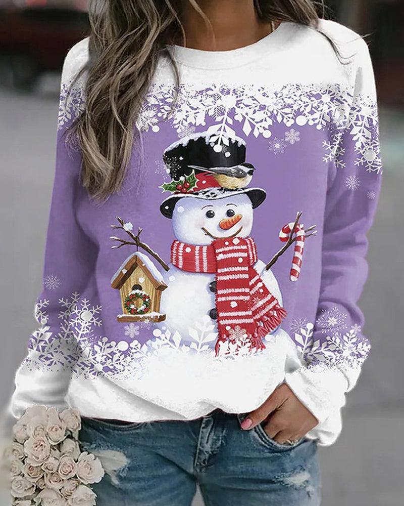 Femme portant un pull violet avec un motif de bonhomme de neige, chapeau noir, écharpe rouge, tenant un sucre d'orge, décor hivernal.