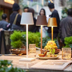 Lampes de table modernes éclairant un dîner élégant avec des plats gastronomiques et des boissons, ambiance chic et conviviale en arrière-plan.