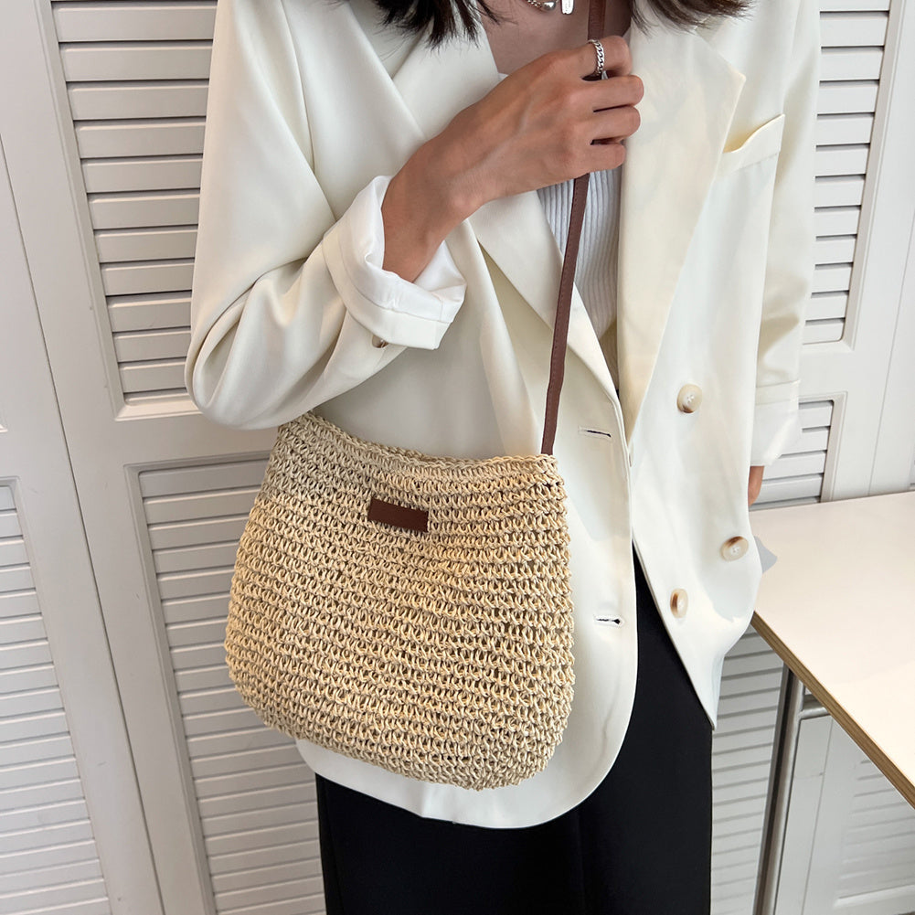 Femme en blazer blanc portant un sac en paille tressée, chic et tendance, idéal pour l'été. Accessoire mode élégant et décontracté.