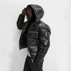 Homme portant une doudoune noire à capuche, style moderne et urbain, sur fond blanc. Mode hiver, veste matelassée tendance.