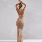 Robe longue transparente à paillettes dorées, femme de dos, cheveux relevés, style élégant et glamour, mode soirée chic.