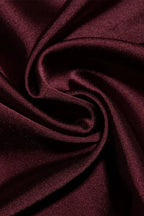 Étoffe satinée bordeaux, texture lisse et brillante, drapée en plis élégants. Tissu luxueux pour mode, décoration ou couture créative.