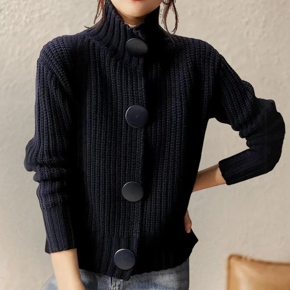 Femme portant un pull en maille noir à col montant avec de grands boutons, style décontracté, mode automne-hiver, fond neutre.