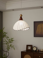 Suspension luminaire moderne en tissu blanc, intérieur salon élégant, plante verte, horloge vintage, cadre mural, ambiance chaleureuse et design.