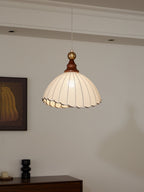 Suspension luminaire vintage avec abat-jour plissé blanc, intérieur moderne, mur blanc, tableau encadré, éclairage décoratif élégant.