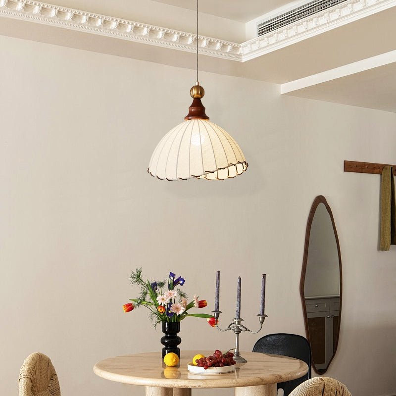Suspension en tissu blanc au-dessus d'une table ronde en bois avec fleurs, bougies et fruits. Décor intérieur élégant et moderne.