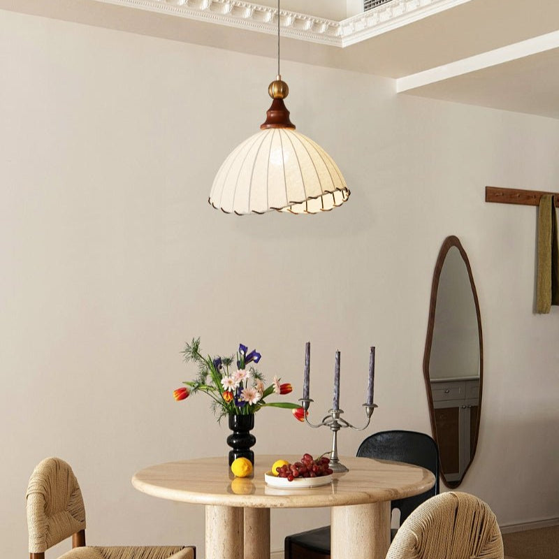 Suspension en rotin au-dessus d'une table ronde en bois avec fleurs, bougies et fruits. Décor intérieur moderne et élégant. Éclairage design.