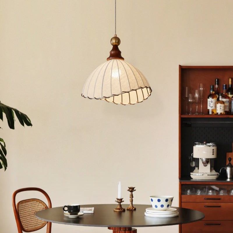 Suspension vintage en tissu blanc au-dessus d'une table ronde avec bougies, tasses et chaise en bois, cuisine moderne avec étagère à boissons.