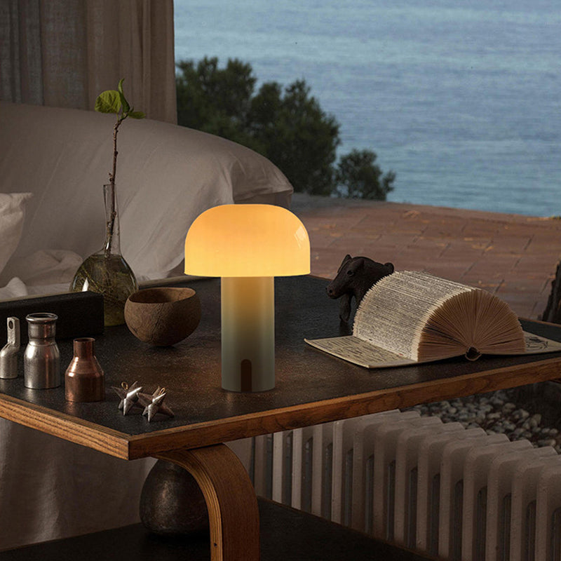 Lampe de table design champignon sur bureau moderne avec vue sur mer, livre ouvert, objets décoratifs en bois et métal, ambiance cosy et élégante.