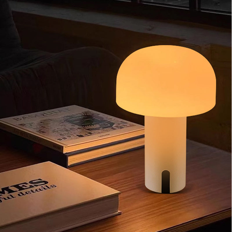 Lampe de table champignon moderne émettant une lumière douce, posée sur une table en bois avec des livres, ambiance chaleureuse et cosy.