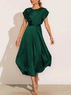 Robe verte élégante en satin, manches courtes, ceinture à la taille, longueur mi-mollet, portée par une femme, style chic et moderne.