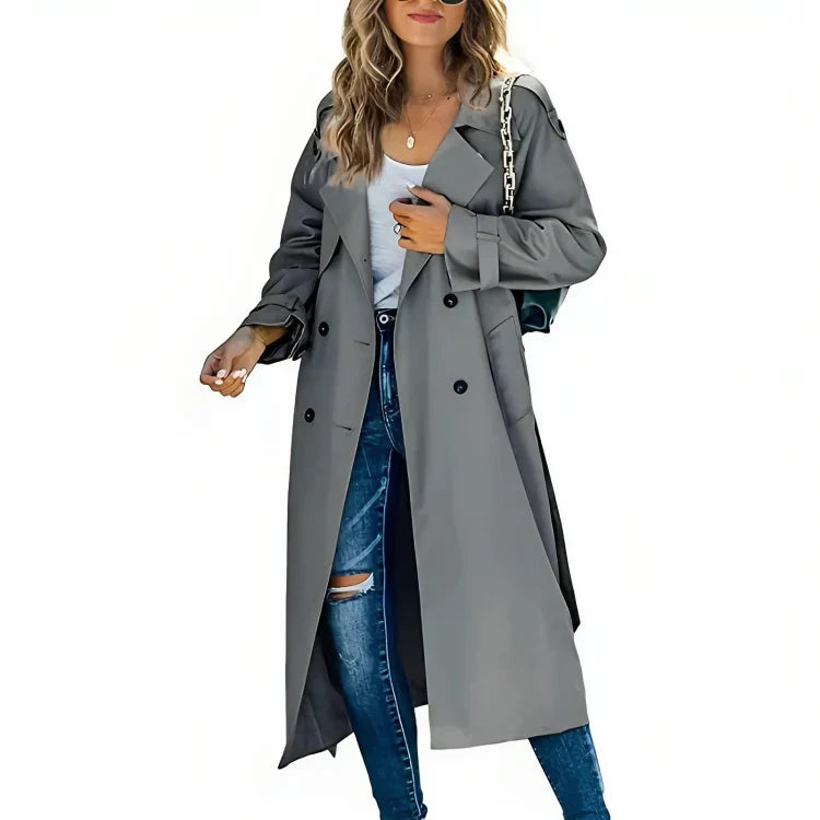 Femme portant un trench-coat gris élégant, chemise blanche et jean déchiré, accessoirisé d'un sac à chaîne argentée. Mode automne chic.