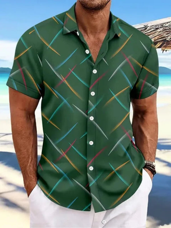 Homme portant une chemise hawaïenne verte à motifs colorés sur une plage ensoleillée, mer turquoise en arrière-plan. Mode estivale décontractée.