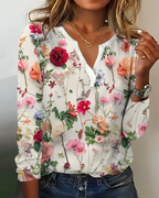 Femme portant une blouse à manches longues avec motif floral coloré, fond blanc. Mode féminine, style décontracté, tendance printemps-été.