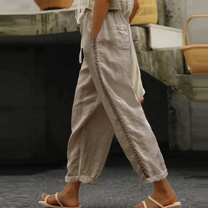 Pantalon en lin beige pour femme, style décontracté, avec poches, porté avec des sandales blanches. Mode estivale confortable et élégante.