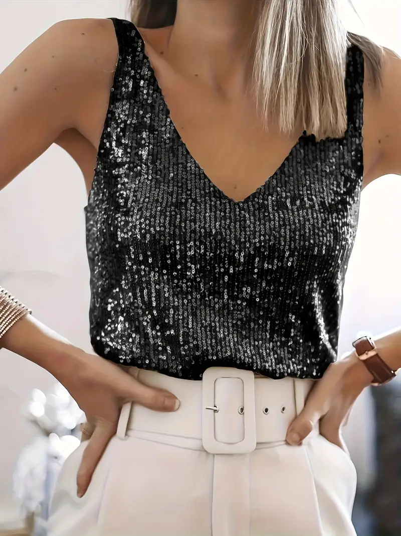 Femme portant un débardeur à paillettes noires et un pantalon blanc avec ceinture large. Mode élégante, tenue de soirée chic, style glamour.
