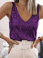 Débardeur violet à paillettes porté par une femme, associé à un pantalon blanc avec ceinture. Mode féminine élégante et tendance.