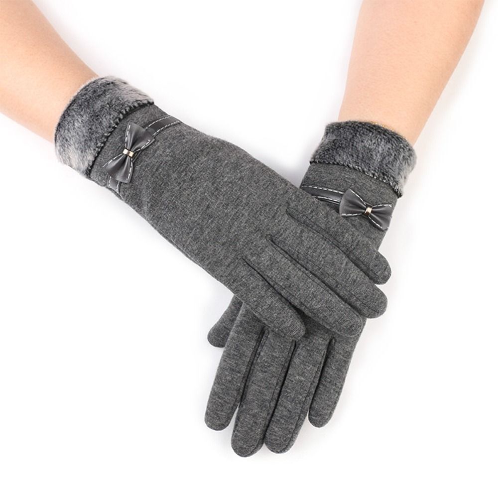 Gants en laine gris avec nœuds décoratifs, doublure en fausse fourrure, portés sur fond blanc. Accessoire hiver élégant et chaud.