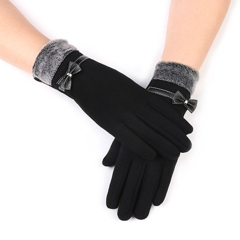 Gants noirs élégants avec nœuds décoratifs, doublure en fourrure grise, portés sur des mains. Accessoire mode hiver chic et tendance.