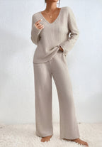 Femme portant un ensemble pull et pantalon en maille beige, style décontracté et confortable, sur fond blanc. Mode automne-hiver, tenue cosy.