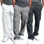 Trois pantalons de jogging pour homme en coton, couleurs blanc, gris clair et gris foncé, avec poches cargo, portés avec des baskets blanches.