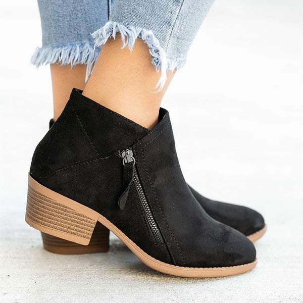 Bottines noires en daim avec talon carré, fermeture éclair latérale, portées avec un jean effiloché. Chaussures tendance automne-hiver femme.