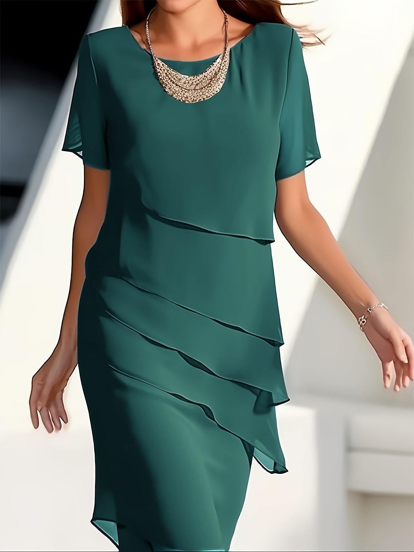 Robe verte élégante à volants superposés, portée par une femme, avec un collier doré. Mode féminine chic, tenue de soirée moderne.
