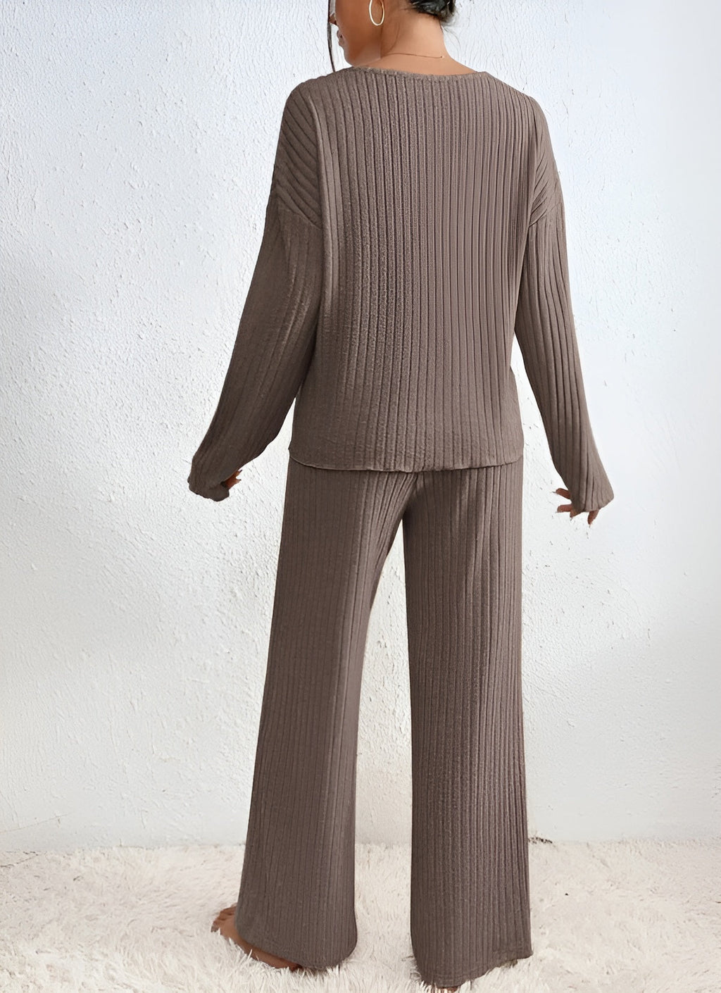 Femme portant un ensemble lounge en tricot marron, pull à manches longues et pantalon large, sur fond blanc. Mode confortable et élégante.