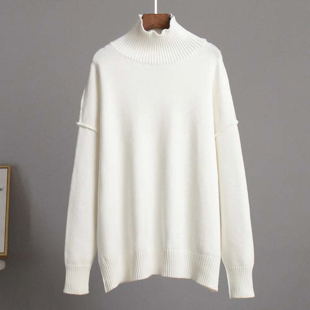 Pull-over blanc en laine, col roulé côtelé, manches longues, style minimaliste, suspendu sur un cintre, fond gris neutre.