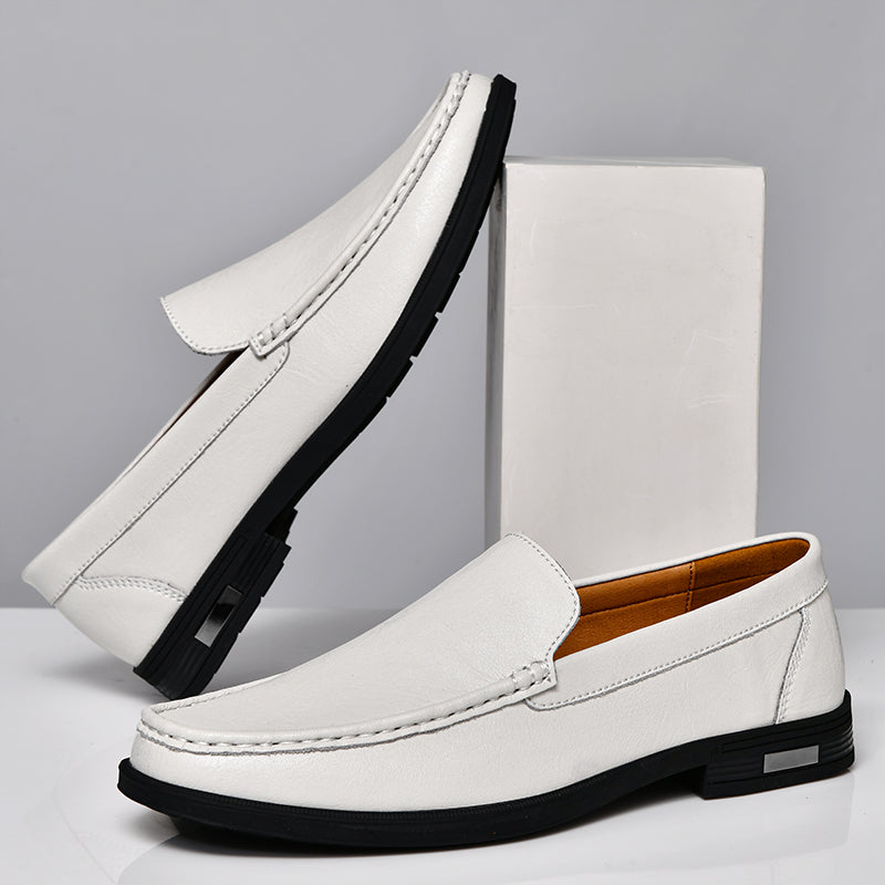 Mocassins blancs élégants pour hommes avec semelle noire, posés sur une boîte blanche. Chaussures en cuir, style moderne et chic.